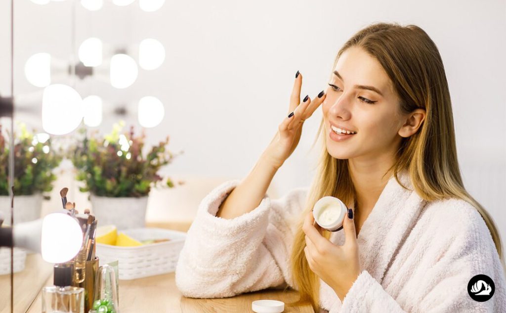 تصویر یک خانم در حال استفاده از کرم دور چشم